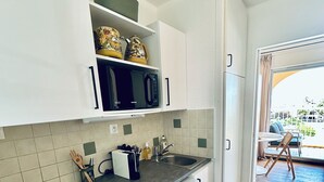Ett modernt kök med vita skåp, en svart mikrovågsugn och en diskmaskin.