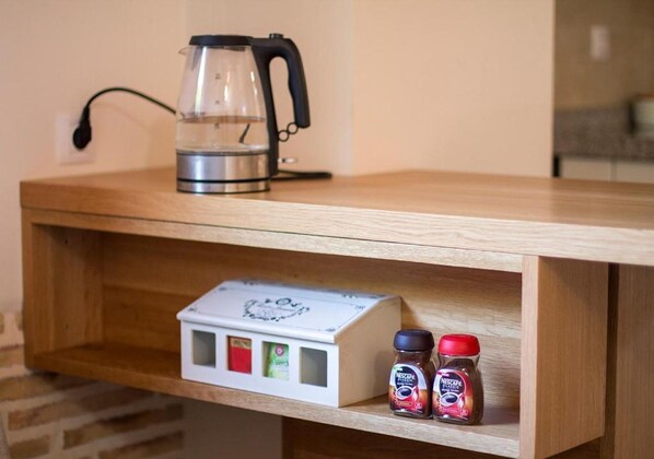 A wooden shelf with a coffee maker, a box of Nescafé Dolce Gusto, and two Nescafé jars.