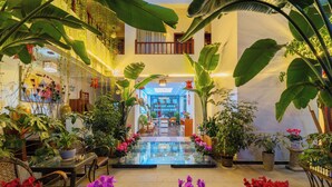 An indoor atrium with a central glass floor, surrounded by potted plants and furniture. - 166 Hotel-Ancient City Mufu Branch (Lijiang)