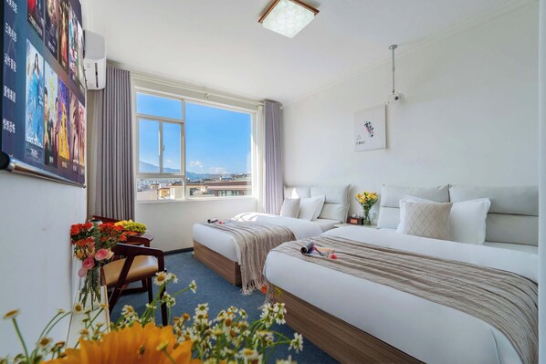 A hotel room with two beds, a desk with a chair, a large window, and a view of the city. - 166 Hotel-Ancient City Mufu Branch (Lijiang)