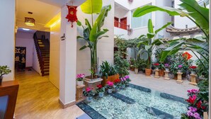 A multi-level indoor space with a central water feature, potted plants, and traditional architectural elements. - 166 Hotel-Ancient City Mufu Branch (Lijiang)