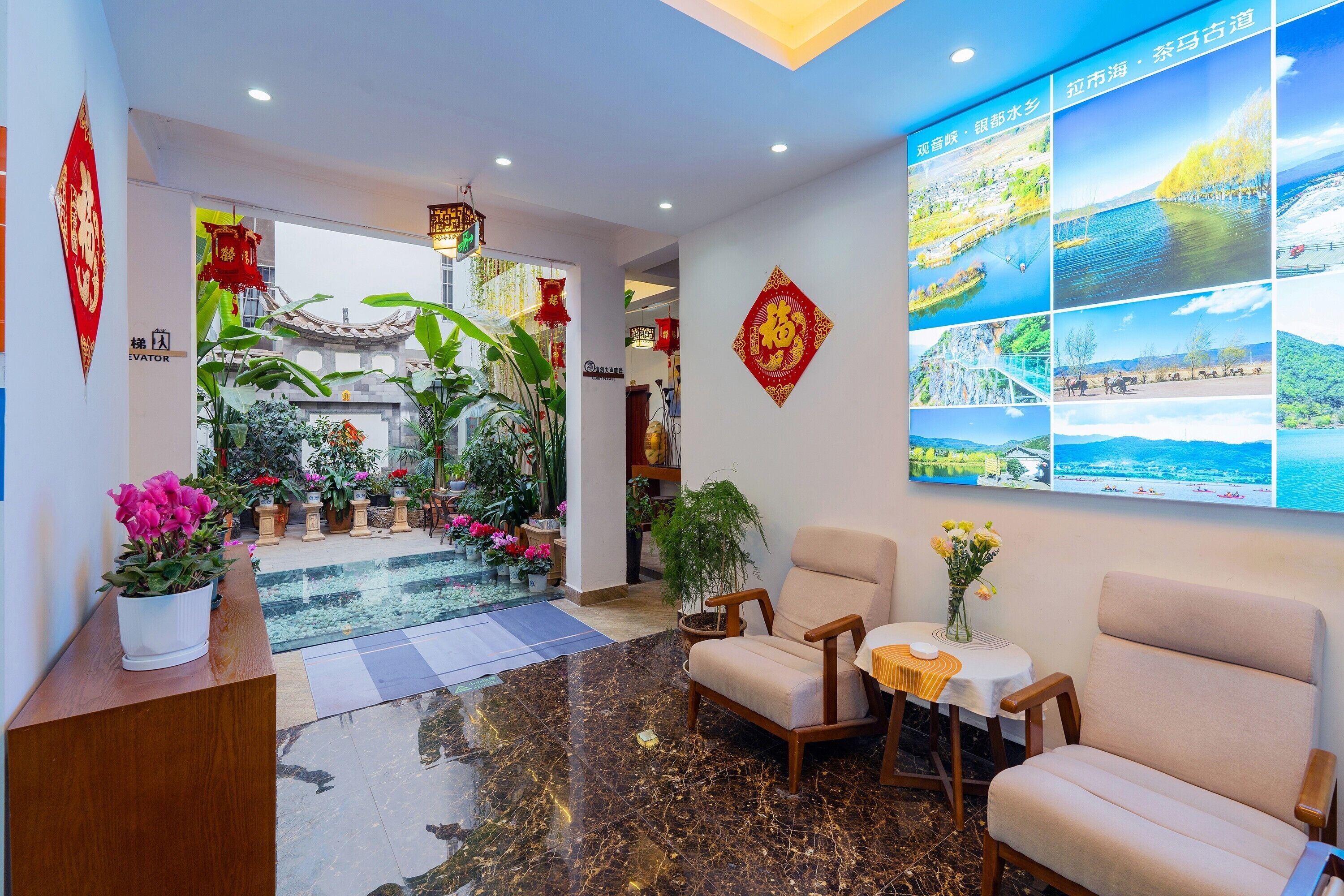 A hotel lobby with a reception desk, seating area, potted plants, and a wall with framed pictures.