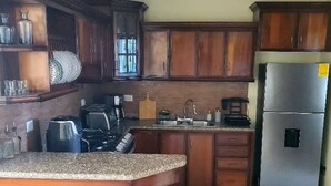 Une cuisine avec des meubles en bois, un plan de travail en granit, un réfrigérateur en acier inoxydable et une machine à café.