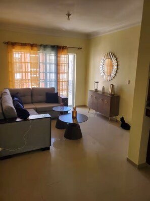 A living room with a sofa, a coffee table, a cabinet, and a wall clock. - Apartment away from the hustle and bustle of the city, with terrace and balcony. (San Francisco de Macorís)