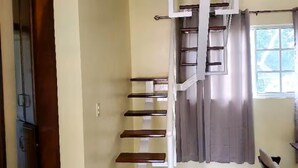 Un escalier en colimaçon avec des marches en bois et des rampes blanches, menant à l’étage supérieur.