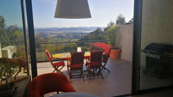 Un balcon avec une table et des chaises, un barbecue et une vue sur le paysage urbain.