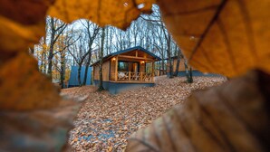 A cabin with a wooden exterior, a porch with seating, and a surrounding leaf-covered ground. - Suma Disanje Boutique Hotel (Sile)