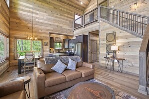 Ein geräumiges Blockhaus-Interieur mit Essbereich, einer Couch, einer Treppe und einer Küche.