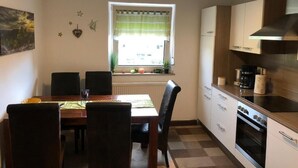 Una cocina compacta con una mesa de comedor, sillas, un ventanal con vistas y una estufa.