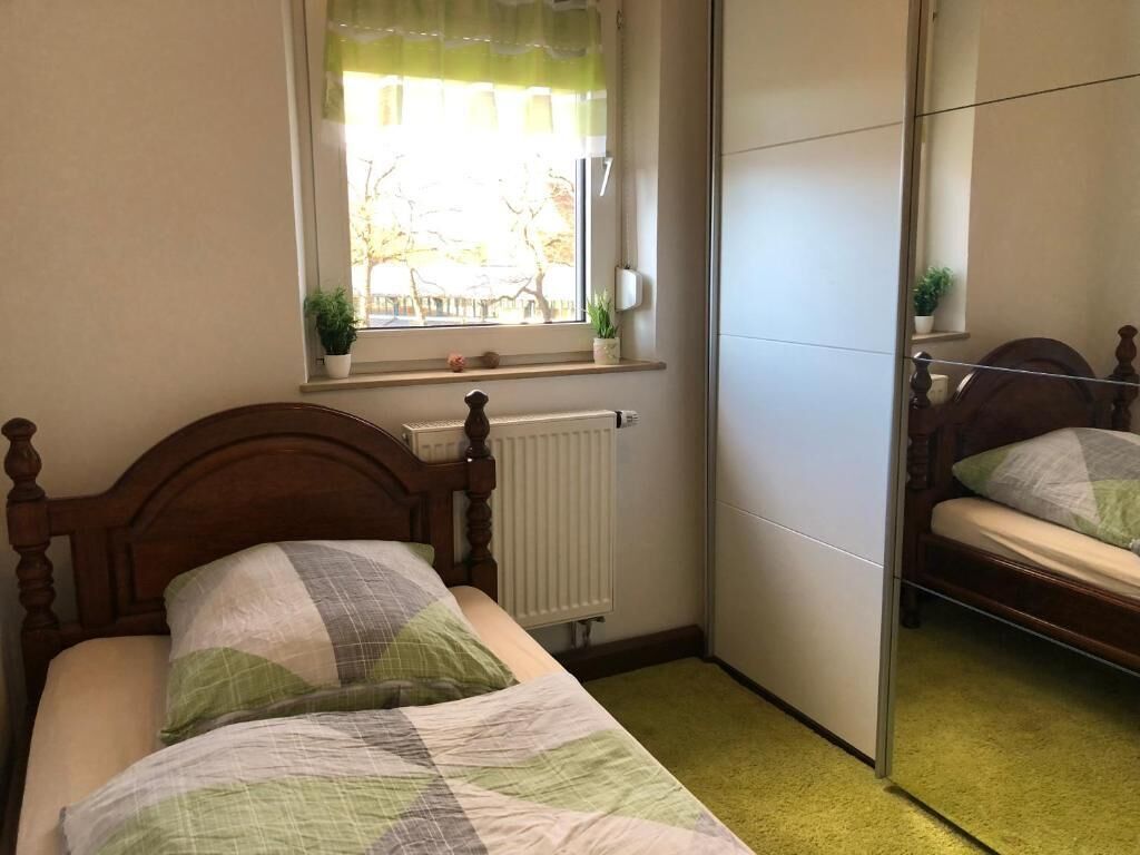 Ein Schlafzimmer mit Bett, Heizkörper, Fenster und Spiegel.