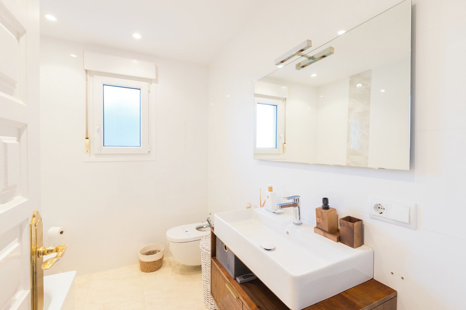 A modern bathroom with a white sink, a large mirror, and a toilet.
