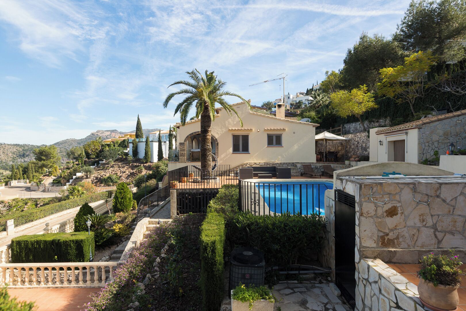 A Mediterranean-style villa with a swimming pool, stone walls, and a view of the surrounding landscape.