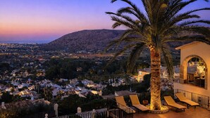 Una piscina con vista a un pueblo y montañas al atardecer.