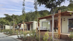 A row of modern, minimalist cabins with large sliding glass doors, wooden decks, and a paved walkway. - Cozy mobile home, pets welcome - 2 guests (Boltaña)