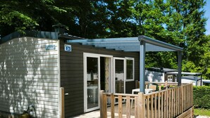 Eine kleine Hütte mit einer Terrasse, einer Veranda und einer Schiebetür.