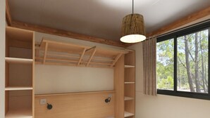 A room with a bed, built-in shelves, a hanging light fixture, and a window with a view of trees.