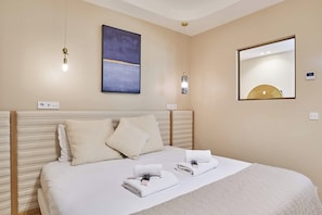 Een hotelkamer met een bed, twee nachtkastjes, een kunstwerk aan de muur, een spiegel en een plafondlamp.