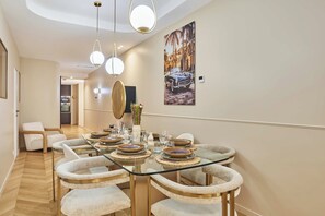 A dining area with a glass table, cushioned chairs, and a painting of a car on the wall. - Apartment AC Saint-germain des Pres Rue de Rennes (Paris)