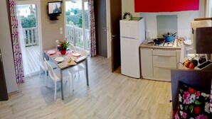 Eine kompakte Küche mit Kühlschrank, Herd und Essecke mit Tisch und Stühlen.