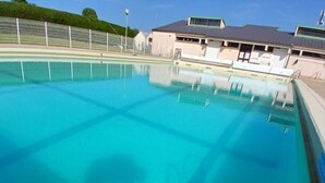 A clear swimming pool with a fence, a building with a flat roof, and a clear sky. - Chalet pet-friendly - 5 guests (Pleaux)
