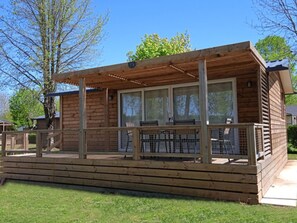 A wooden cabin with a covered deck, large windows, and a fenced outdoor area.