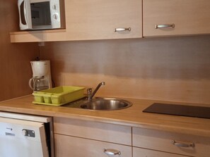 A kitchen with a microwave, coffee maker, sink, and a green dish rack.