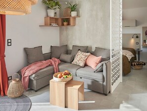 Ein modernes Wohnzimmer mit einem grauen Sofa, einem Holztisch und einer Obstschale.