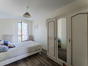 Ein Schlafzimmer mit Bett, Kleiderschrank, Heizkörper, Fenster und einer Pendelleuchte.