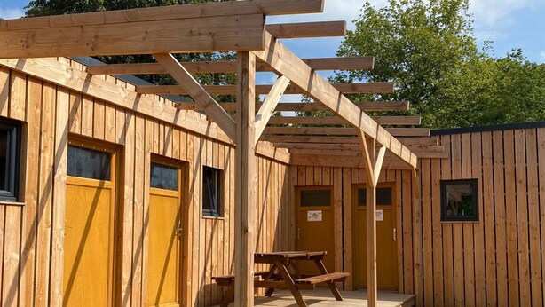 Eine Holzhütte mit einer Veranda, zwei Türen und einem Picknicktisch.