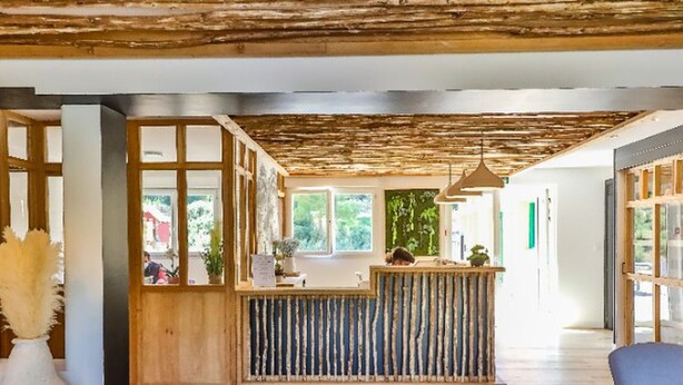 Ein Empfangsbereich mit einem Holzbüro, einem großen Fenster und einem blauen Sessel.
