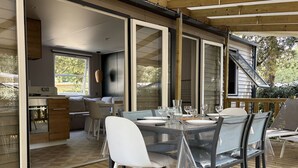 Ein Essbereich im Freien mit einem Tisch für vier Personen, umgeben von Stühlen und einer Holzterrasse.
