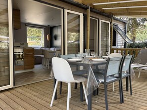 Ein Essbereich im Freien mit einem Tisch für vier Personen, umgeben von Stühlen und einer Holzterrasse.