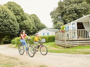 Two people riding bicycles on a gravel path with a mobile home in the background. - Cozy mobile home, pets allowed - 7 guests (Bieuzy)