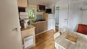 Een kleine keuken met een magnetron, kookplaat en kastjes.