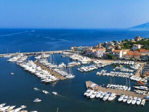 A marina with numerous boats docked, a coastal town with buildings, and a mountain in the background. - Mobile home, pets allowed - 2 guests (Saint-Florent)