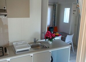 A compact kitchenette with a sink, a small countertop, and a chair. - Mobile home, pets allowed - 2 guests (Saint-Florent)