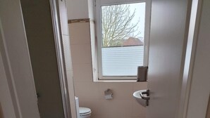 Een compacte badkamer met toilet, wastafel en raam.