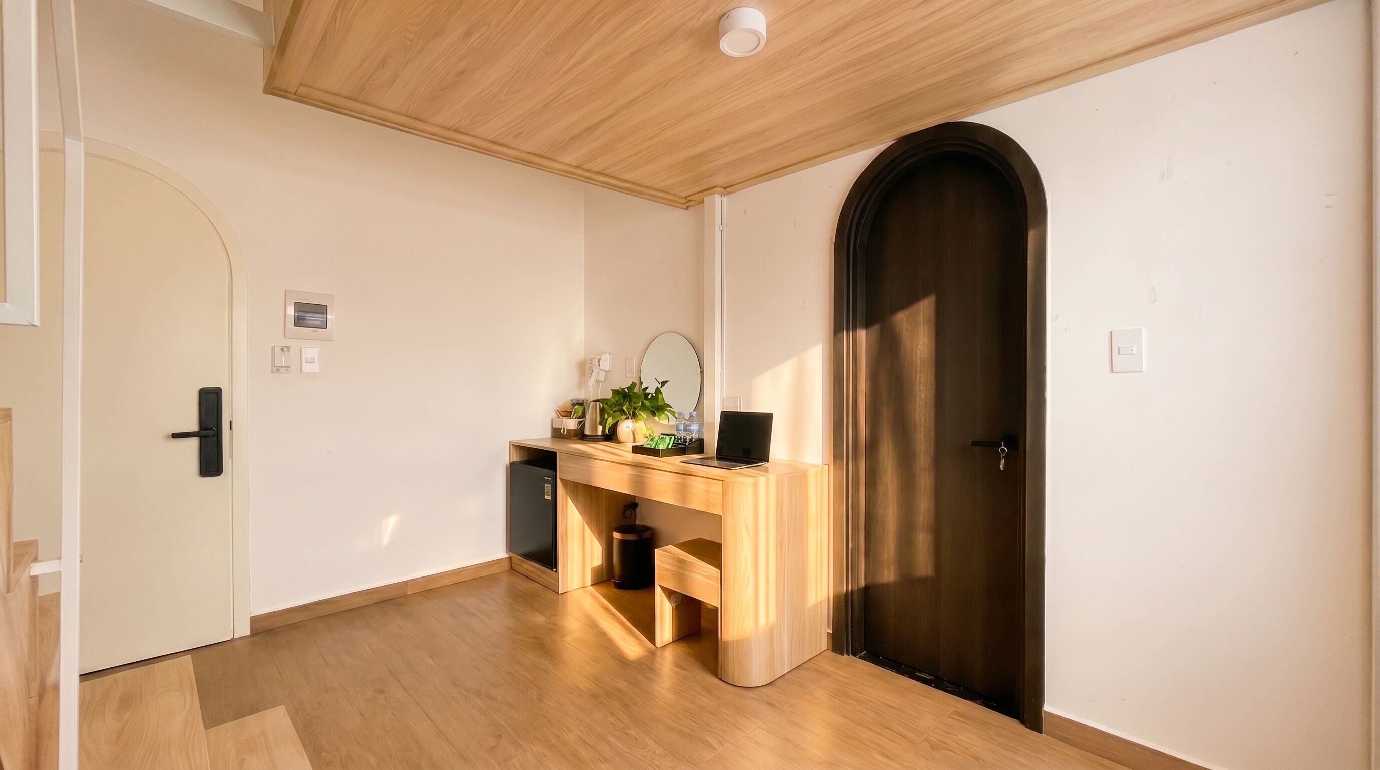 Una habitación con un escritorio de madera, una puerta oscura y un piso de color claro.
