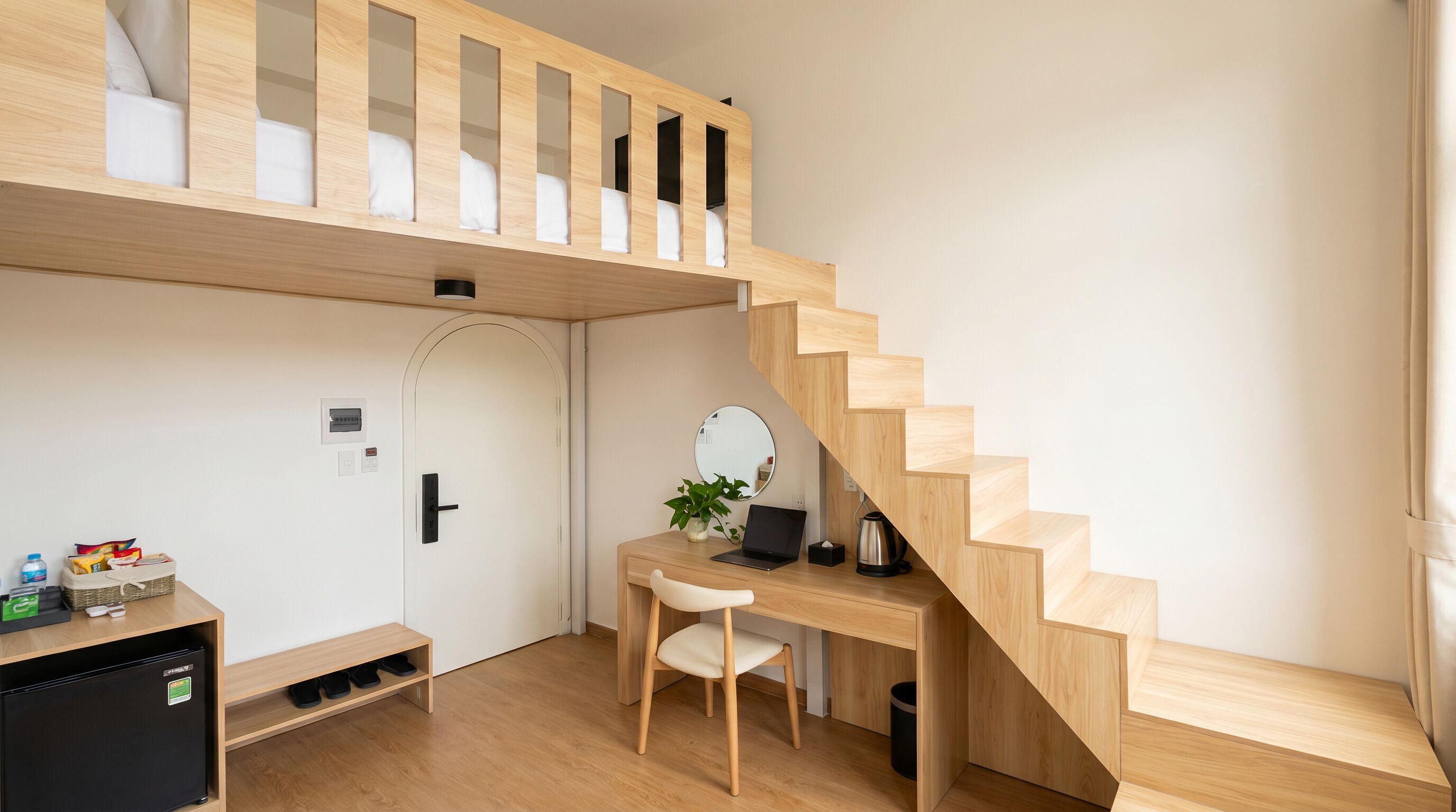 A modern room with a bunk bed, a desk with a chair, a laptop, a kettle, and a small plant.