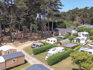 A campground with RVs, a small wooden building, and a large tree. - Mobile home pets welcome - 4 guests (Perros-Guirec)