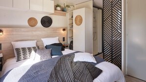 Un dormitorio con cama, mesitas de noche, armario, zona de ducha y un panel decorativo en la pared.