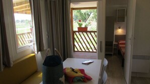 Een kamer met een tafel, een stoel, een bankje, een bed en uitzicht op een tuin.