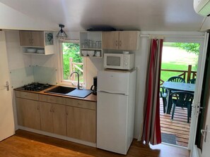 A compact kitchen with a gas stove, sink, white cabinets, a microwave, and a refrigerator. - Mobile home with AC - 6 guests (Monplaisant)