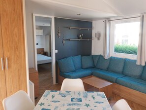 A compact room with a sofa, a table, and a bed. - Comfortable mobile home - 4 guests (Sireuil)
