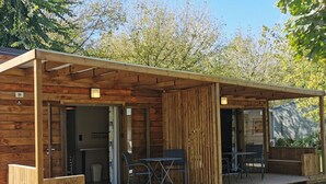 Eine Holzhütte mit überdachter Terrasse, einem Essbereich und einem Lounge-Sessel.