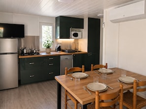 Une cuisine moderne avec une table à manger pour quatre personnes, un four encastré et un four à micro-ondes.