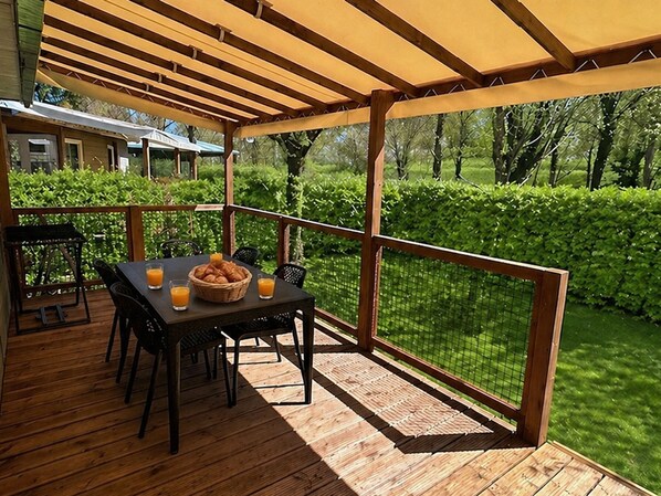 Une terrasse extérieure abritée, avec une table, des chaises et un panier de pain.