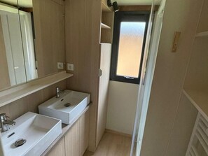 Un baño pequeño con dos lavamanos, un espejo y una ventana.