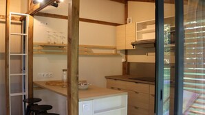 A compact kitchen with wooden beams, a built-in bar stool area, and a window with blinds. - Cozy chalet, pets allowed - 7 guests (Sauxillanges)