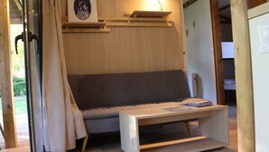 A compact room with a sofa, a small table, and a wall-mounted shelf. - Cozy chalet, pets allowed - 7 guests (Sauxillanges)